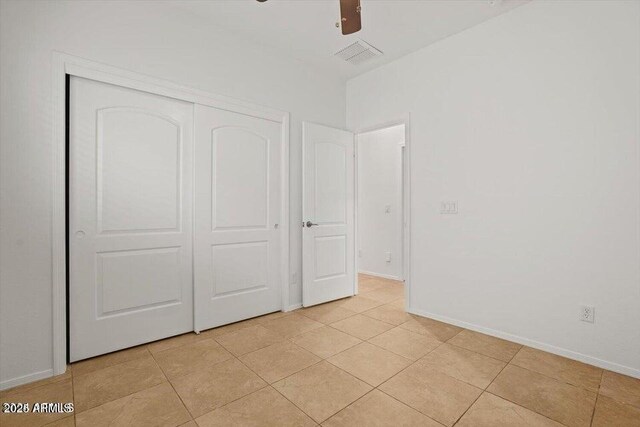 unfurnished bedroom featuring light tile patterned floors, a closet, and ceiling fan