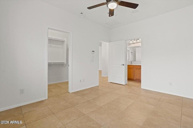 unfurnished bedroom featuring a spacious closet, a closet, ceiling fan, and ensuite bathroom