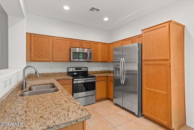 kitchen featuring light stone countertops, light tile patterned floors, stainless steel appliances, and sink