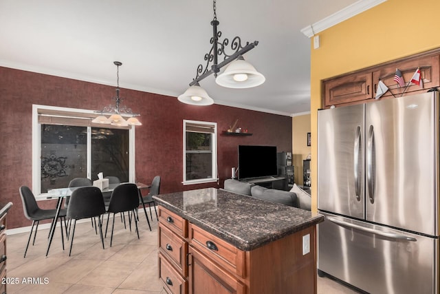 kitchen featuring dark stone countertops, light tile patterned floors, freestanding refrigerator, ornamental molding, and a center island