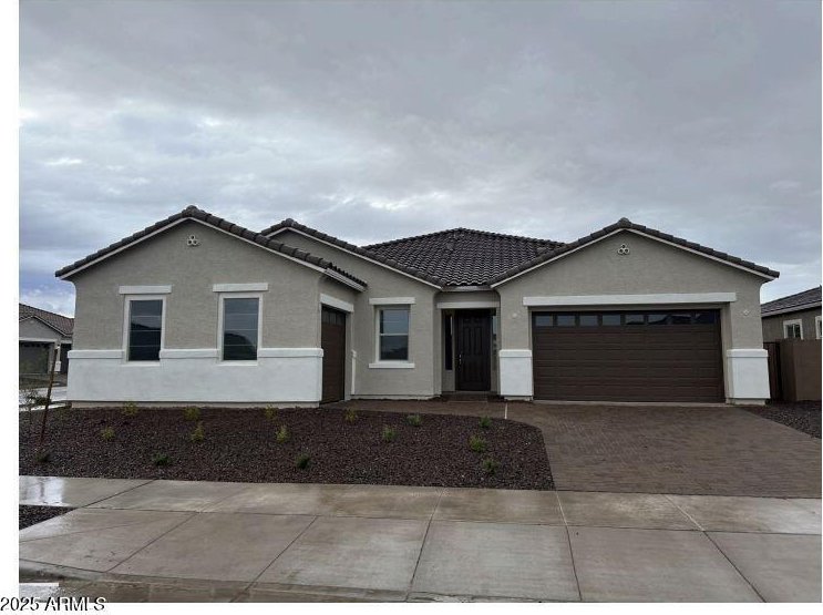 view of front of property with decorative driveway, an attached garage, stucco siding, and a tile roof