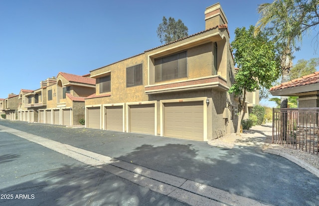 5122 E Shea Blvd Unit 1020, Scottsdale, AZ 85254 - view of front of house with community garages, fence, a chimney, and stucco siding