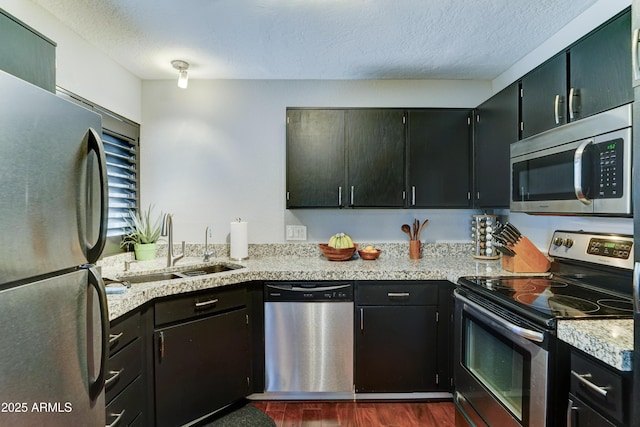 5122 E Shea Blvd Unit 1020, Scottsdale, AZ 85254 - kitchen featuring a sink, appliances with stainless steel finishes, dark cabinetry, a textured ceiling, and dark wood-style flooring