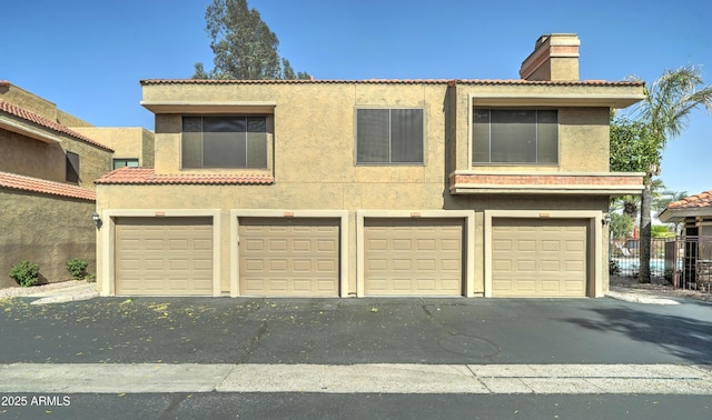5122 E Shea Blvd Unit 1020, Scottsdale, AZ 85254 - view of front of house featuring a tiled roof, an attached garage, a chimney, and stucco siding