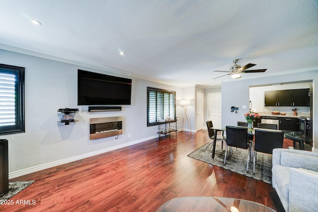 5122 E Shea Blvd Unit 1020, Scottsdale, AZ 85254 - living area featuring ornamental molding, a glass covered fireplace, dark wood-style floors, baseboards, and ceiling fan