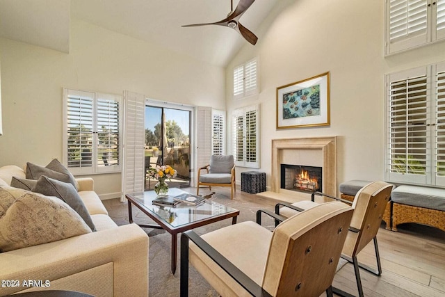 living room featuring a fireplace, high vaulted ceiling, light wood-type flooring, and ceiling fan