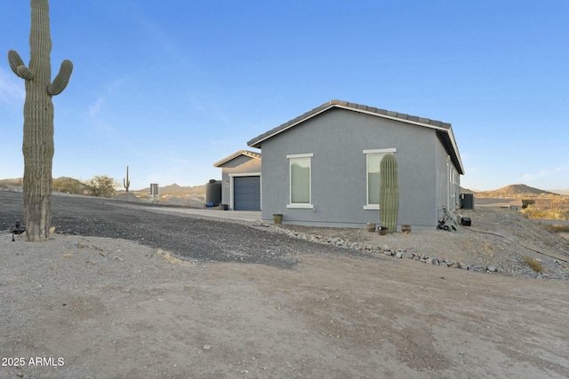 view of property exterior with an attached garage, driveway, and stucco siding