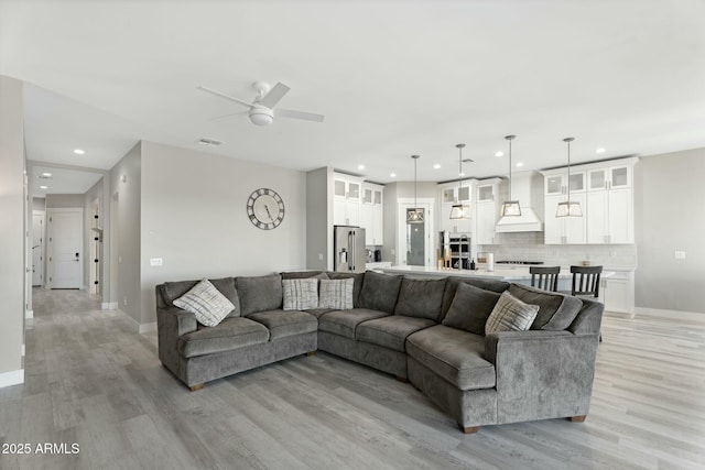 living room featuring ceiling fan, recessed lighting, visible vents, baseboards, and light wood-type flooring