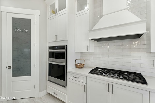 kitchen with light countertops, appliances with stainless steel finishes, backsplash, and custom exhaust hood