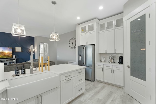 kitchen featuring tasteful backsplash, high end fridge, light wood-style flooring, glass insert cabinets, and white cabinetry