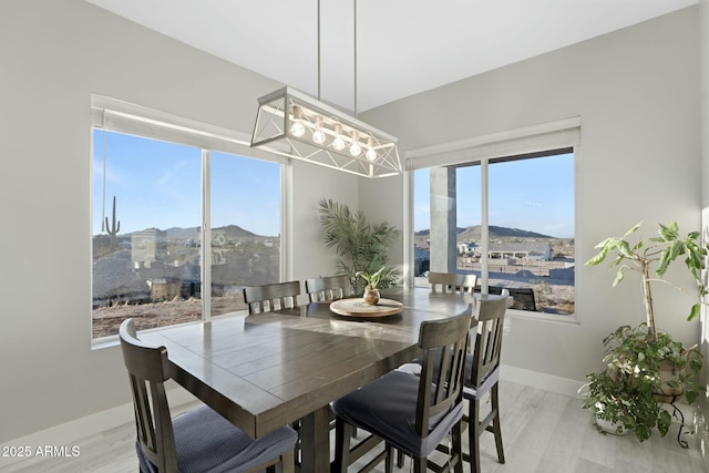 dining space with light wood finished floors, baseboards, and a mountain view