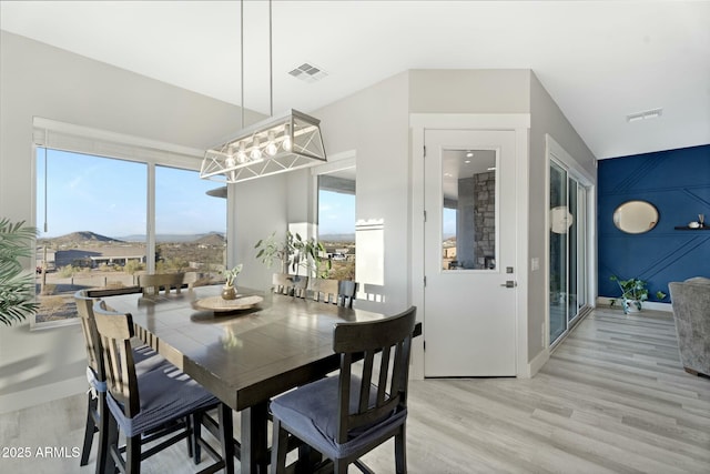 dining area featuring light wood-type flooring, visible vents, and baseboards