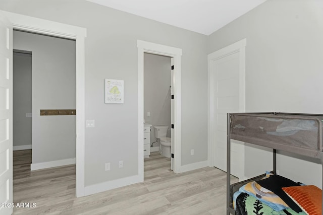 bedroom featuring ensuite bath, baseboards, and wood finished floors