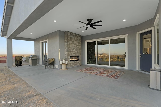 view of patio with a grill, an outdoor stone fireplace, and a ceiling fan