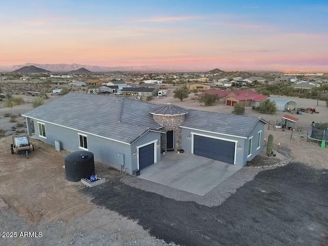 view of front of house with a garage, concrete driveway, a mountain view, and stucco siding