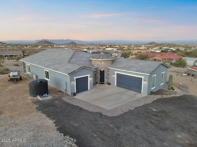 single story home with stone siding, concrete driveway, an attached garage, and stucco siding