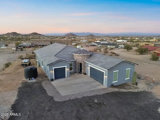 ranch-style home featuring a garage, driveway, a mountain view, and stucco siding