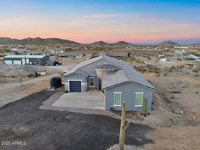 view of front of house featuring concrete driveway, an attached garage, a mountain view, and stucco siding