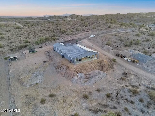 aerial view at dusk featuring a desert view and a mountain view