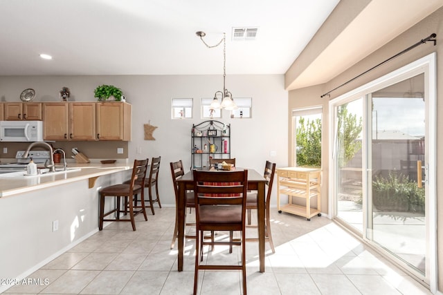 dining room featuring sink, light tile patterned flooring, and a notable chandelier