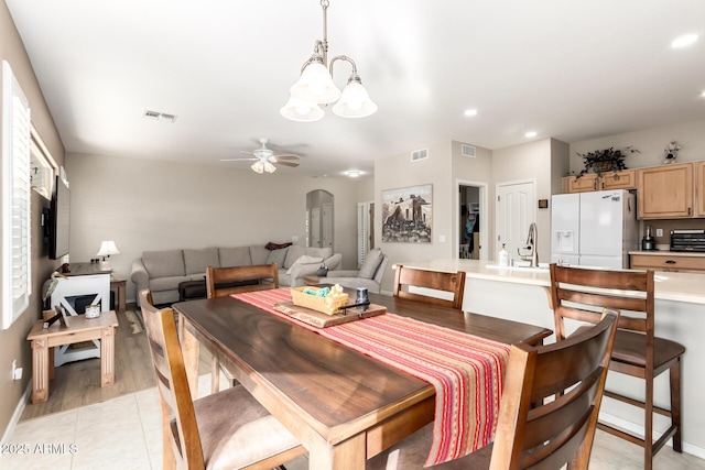 tiled dining space with ceiling fan with notable chandelier and sink