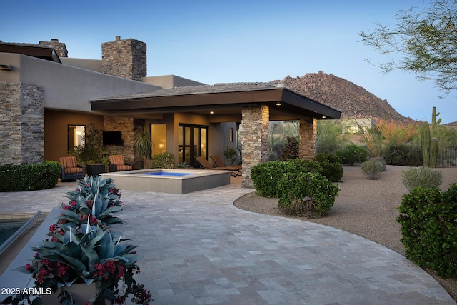 10205 E Happy Valley Rd, Scottsdale, AZ 85255 - rear view of property featuring an in-ground hot tub, stone siding, a patio, a mountain view, and stucco siding