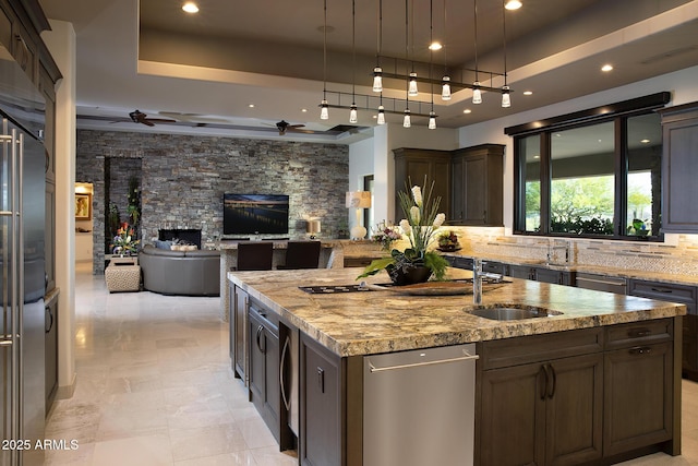 10205 E Happy Valley Rd, Scottsdale, AZ 85255 - kitchen with a tray ceiling, a ceiling fan, a sink, an island with sink, and a stone fireplace