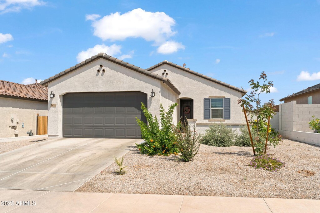view of front of home with a tile roof, driveway, fence, a garage, and stucco siding