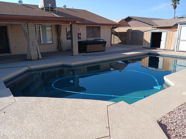 view of swimming pool with a shed, a patio, and a hot tub