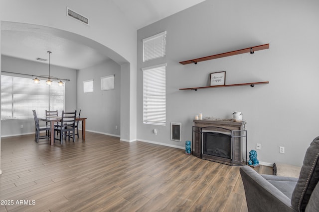 1405 S Honeysuckle Cir, Gilbert, AZ 85296 - living area featuring a fireplace, arched walkways, wood finished floors, baseboards, and high vaulted ceiling