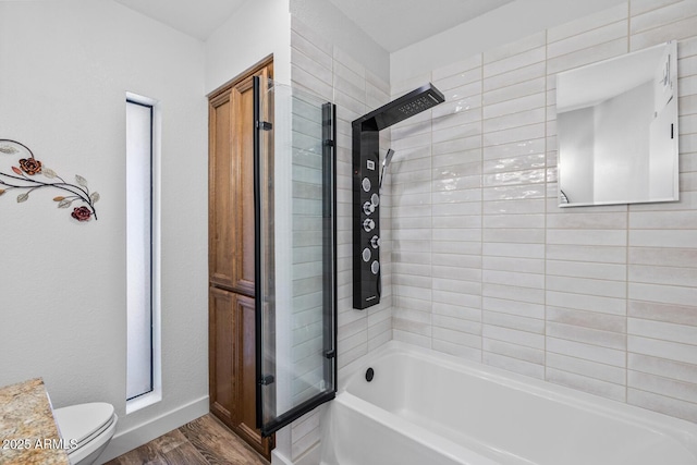 full bath with toilet, bathing tub / shower combination, wood finished floors, and baseboards