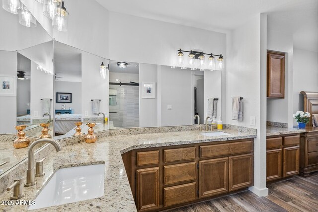 bathroom featuring a stall shower, double vanity, a sink, and wood finished floors