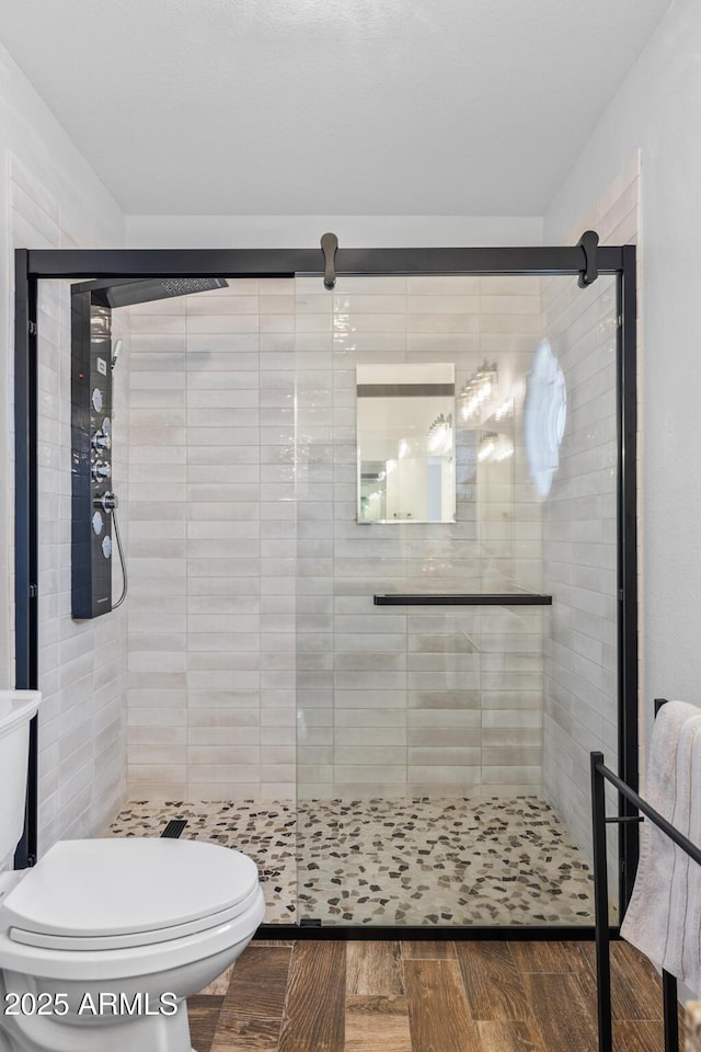 full bath with a stall shower, toilet, and wood finished floors