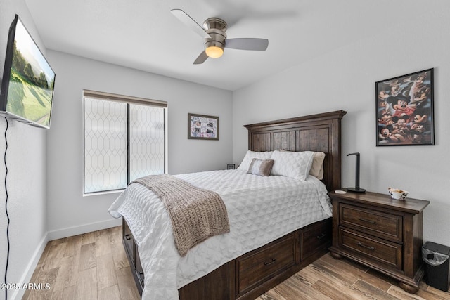 bedroom with ceiling fan, light wood-style flooring, and baseboards