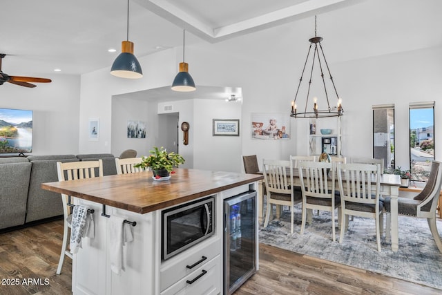kitchen with stainless steel microwave, beverage cooler, wooden counters, open floor plan, and dark wood finished floors