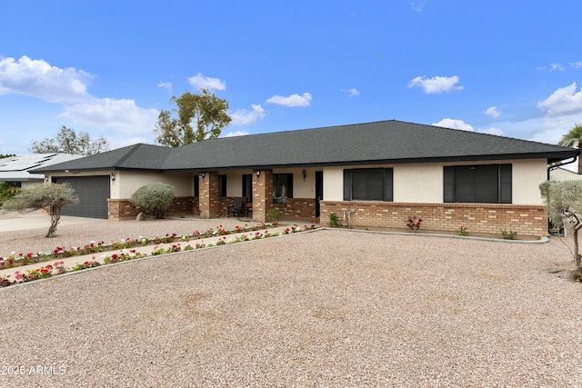 single story home featuring concrete driveway, brick siding, a garage, and stucco siding