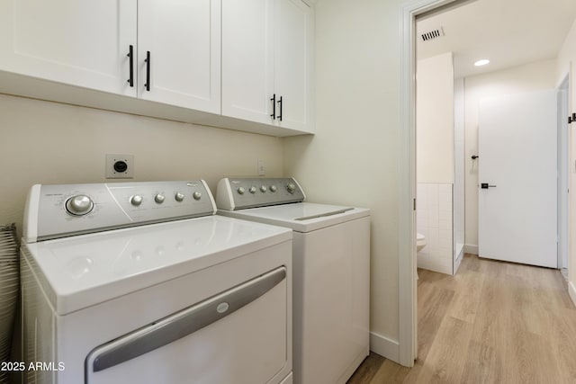 clothes washing area featuring visible vents, cabinet space, light wood-style floors, and washing machine and clothes dryer