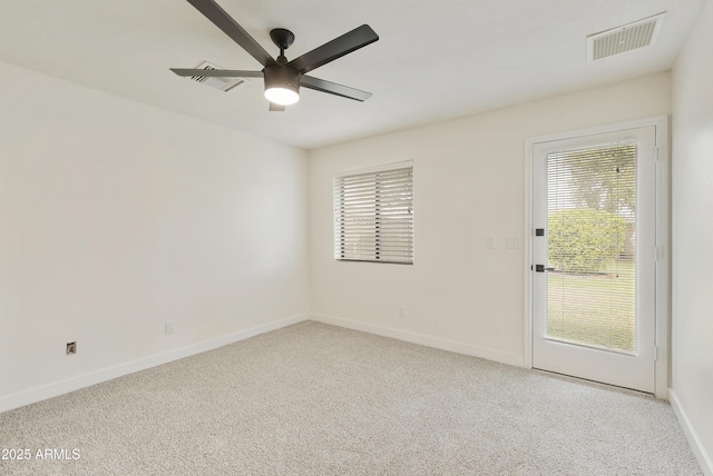 spare room with visible vents, light colored carpet, baseboards, and a ceiling fan