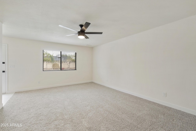 spare room featuring ceiling fan, baseboards, and light carpet