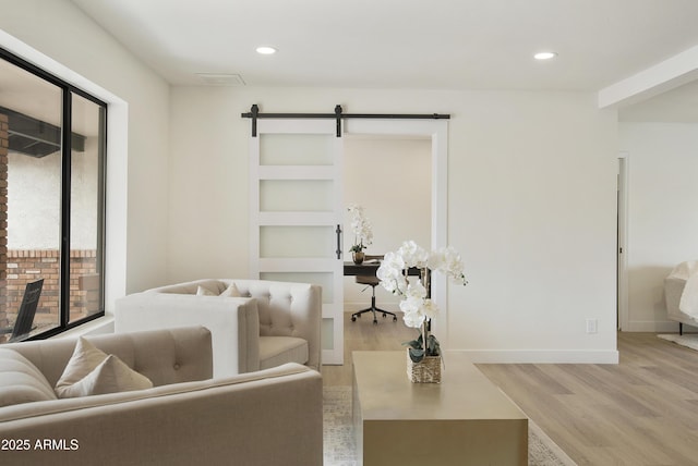 living room featuring recessed lighting, a barn door, baseboards, and light wood-style flooring