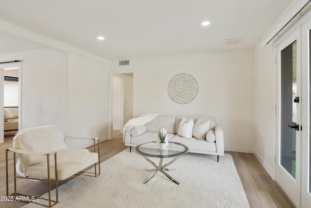 living area with recessed lighting, wood finished floors, visible vents, and baseboards