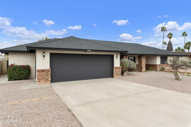 ranch-style house featuring brick siding, an attached garage, a shingled roof, stucco siding, and driveway