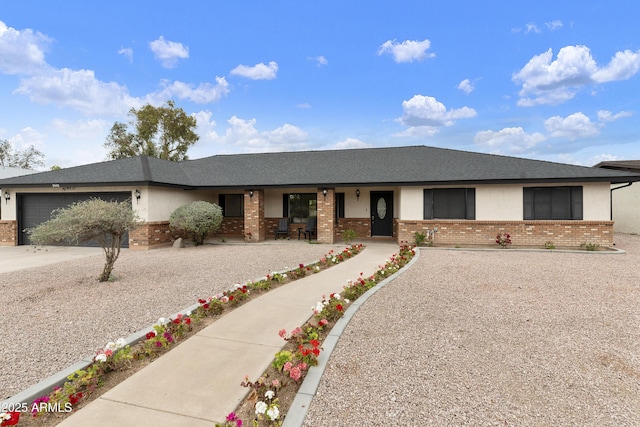 ranch-style home featuring brick siding, driveway, an attached garage, and roof with shingles