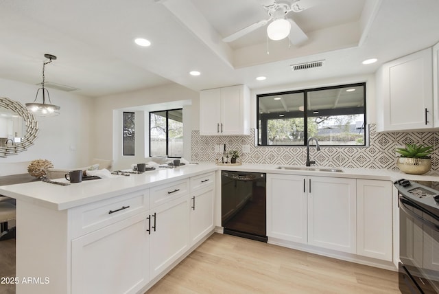 kitchen with visible vents, a peninsula, a tray ceiling, a sink, and black appliances