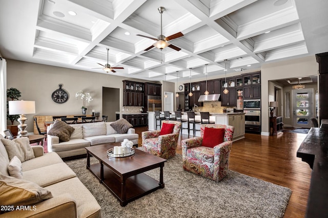 living room with coffered ceiling, ceiling fan, dark hardwood / wood-style flooring, and beam ceiling