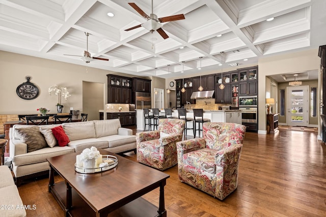 living room featuring coffered ceiling, beam ceiling, dark wood-type flooring, and ceiling fan