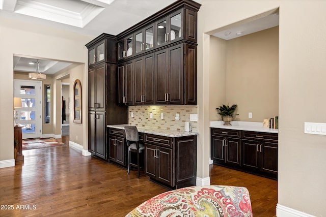 kitchen with pendant lighting, dark hardwood / wood-style floors, dark brown cabinetry, tasteful backsplash, and a raised ceiling