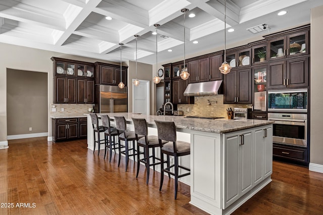 kitchen with decorative light fixtures, light stone counters, black appliances, dark brown cabinets, and a spacious island