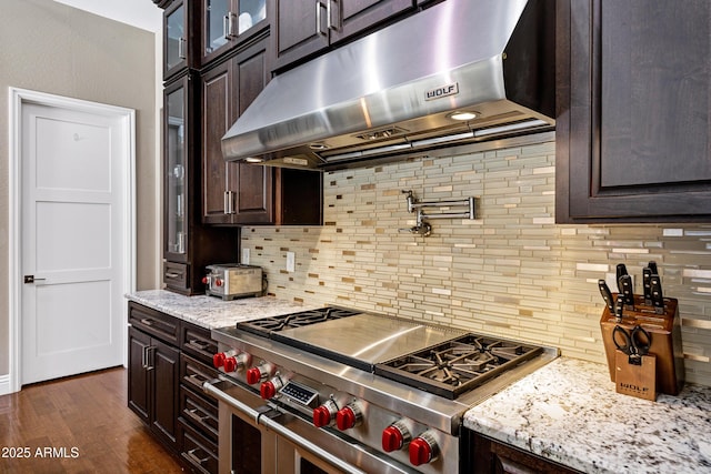 kitchen featuring dark hardwood / wood-style floors, decorative backsplash, double oven range, light stone counters, and dark brown cabinets