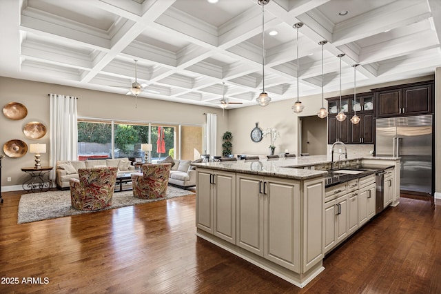 kitchen featuring appliances with stainless steel finishes, pendant lighting, sink, dark stone counters, and a kitchen island with sink